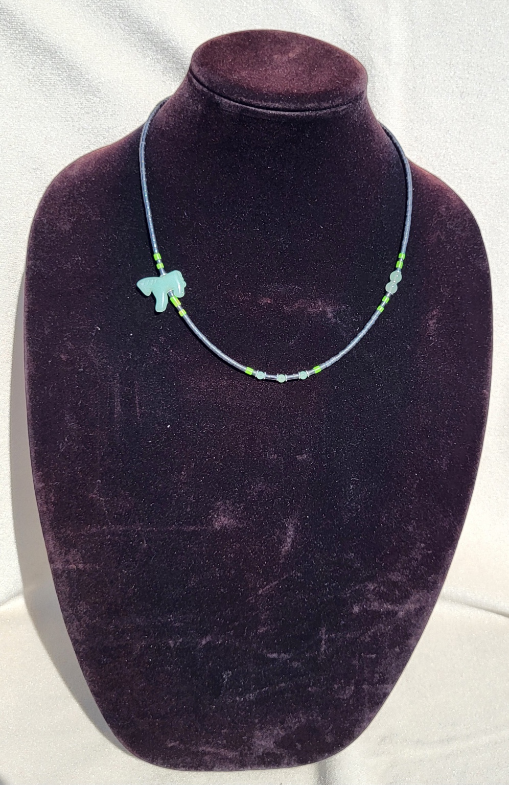 Grey beaded necklace with a carved green aventurine horse and lime accents