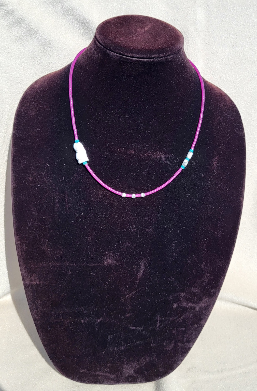 Magenta beaded necklace with carved white stone bear and turquoise accents