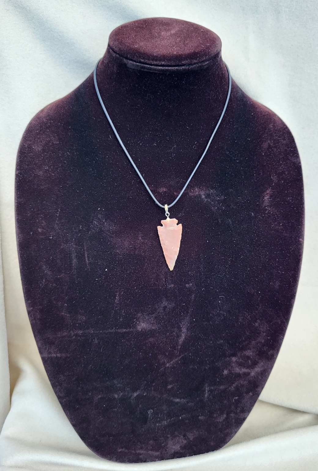 Hand-shaped rose quartz arrowhead pendant on a fine black cord necklace