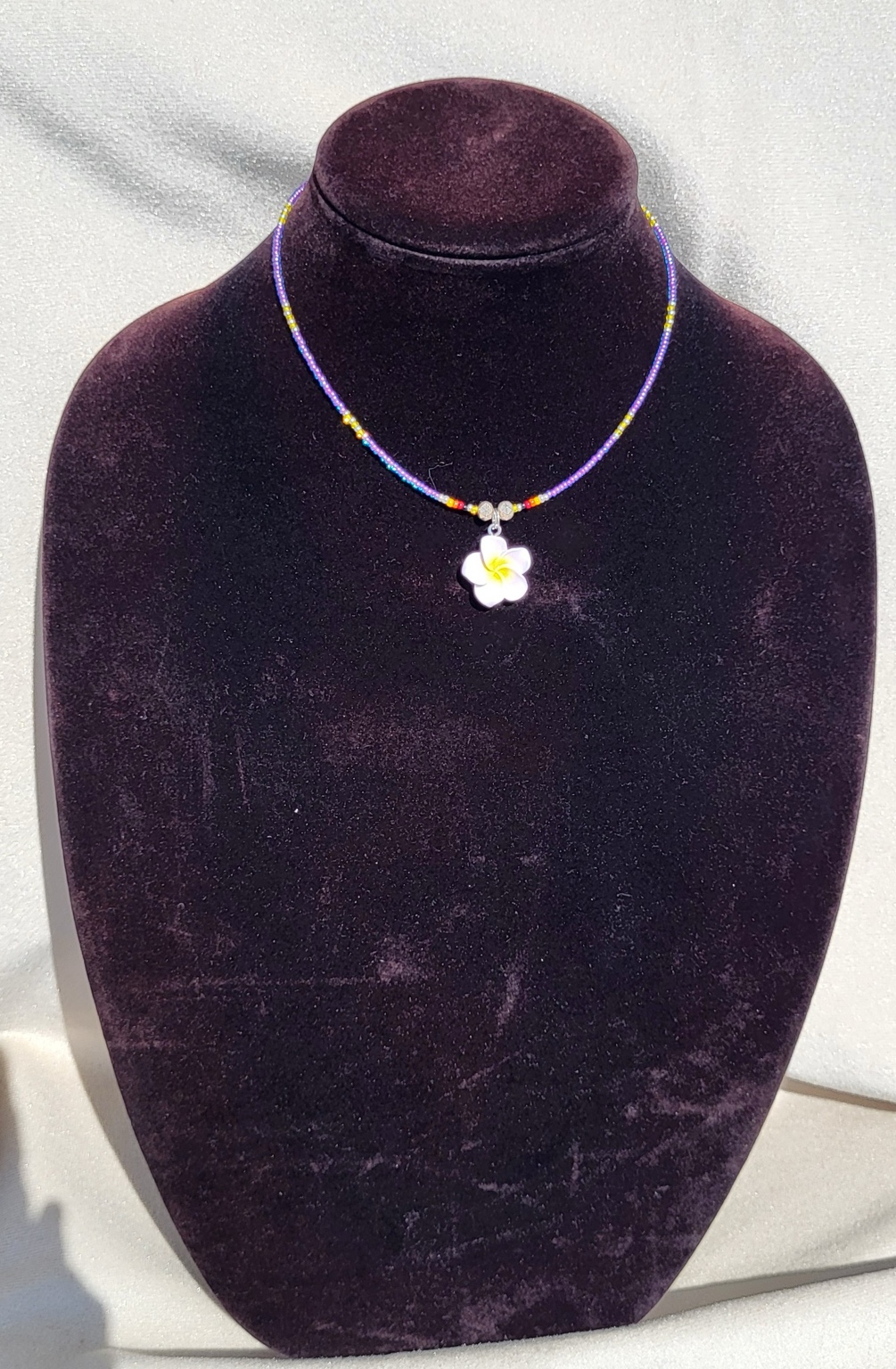 Lavender seed bead necklace with a white and yellow plumeria pendant