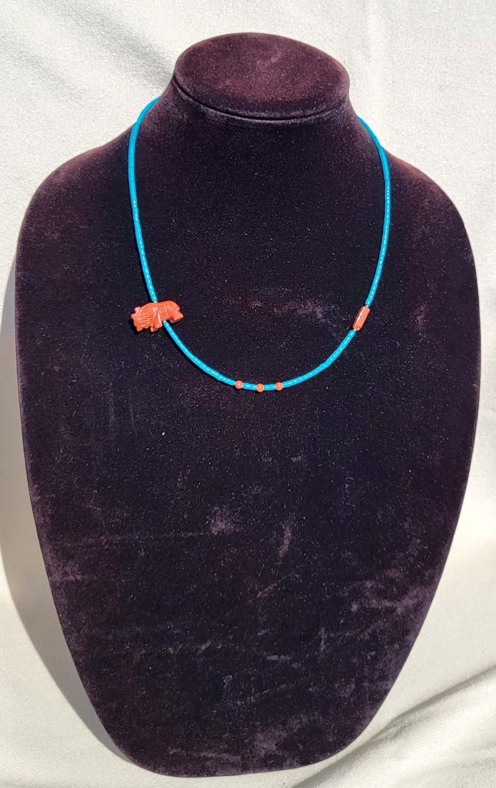 Bright turquoise tube bead necklace with a carved coral bear fetish